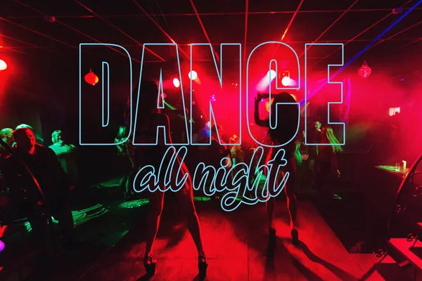 Надпись Dance All Night на фоне размытых силуэтов танцоров го-го на сцене — стоковое фото