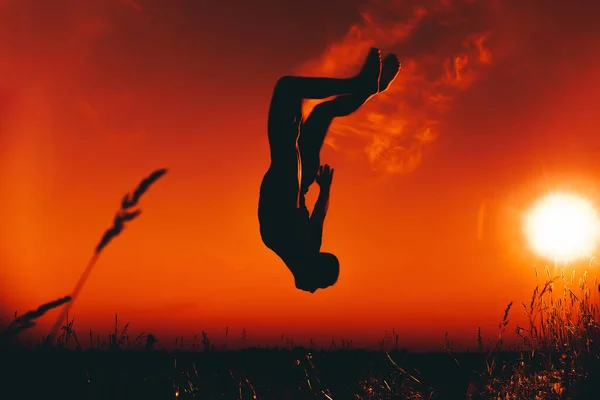 Silhouette eines männlichen Athleten, der springt und Purzelbäume schlägt — Stockfoto