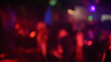 Bir gece kulübünün dans pistinde dans eden kalabalığın bulanık silüetleri.