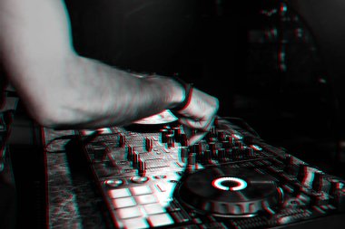 DJ, bir gece kulübünde profesyonel bir kontrol panosunda müzik karıştırıyor.