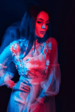 Esmer bir kızın portresi koyu bir arka planda, bulanık bir etkiye sahip bir elbise içinde.