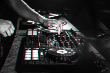 DJ, bir gece kulübünde profesyonel bir kontrol panosunda müzik karıştırıyor.