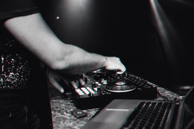 Bir gece kulübündeki konserde mikser konsolunda elektronik müzik çalan eller.