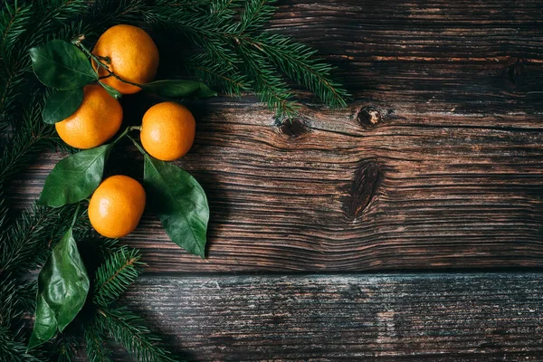 オレンジみかんとモミの枝を持つお祝いのクリスマスの木製の背景 — ストック写真