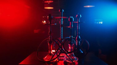 Geleneksel Doğu Türkçe gevşemesi için restoranın masasında cam mataralar ve metal kaseler bulunan hookahlar.