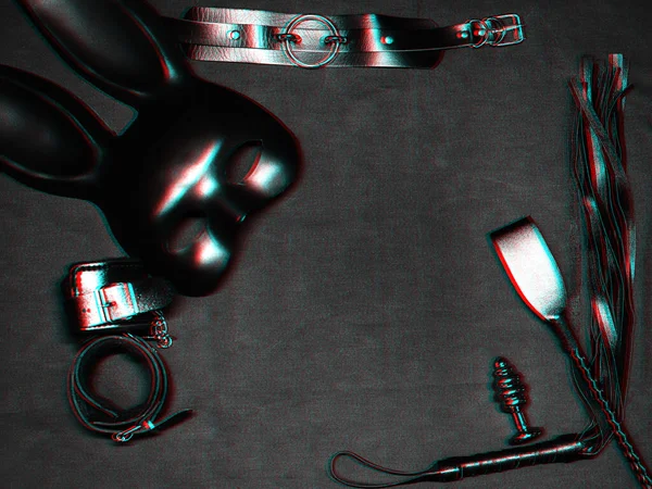 Набор секс-игрушек на черном фоне. Кожаный кнут, наручники, удушитель, маска и металлическая анальная пробка для БДСМ секса и ролевых игр — стоковое фото