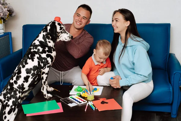 Felice famiglia caucasica con un cane dalmata sono impegnati nel lavoro creativo a casa e divertirsi — Foto Stock