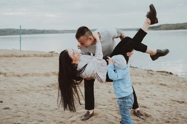 Joven familia feliz divirtiéndose en la arena en la playa —  Fotos de Stock