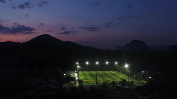 Antenn. Ovanifrån av vacker bergsutsikt och två fotbollsplaner nattetid. — Stockvideo