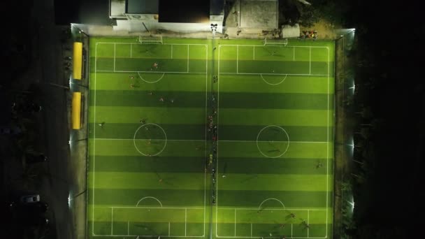 AERIAL. Camera moving from down to top. Top view of two football fields at night time. Teams playing at football. — Stock Video