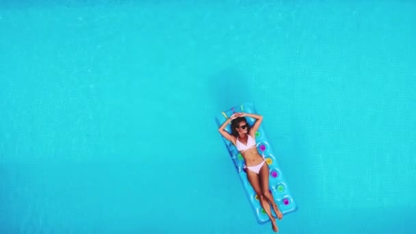 AERIAL. Top view. Static video. Outdoor lifestyle close-up portrait of young pretty sexy girl posing with neon bright swimming mattress at the pool, wearing bikini and sunglasses, relax and having fun — Stock Video