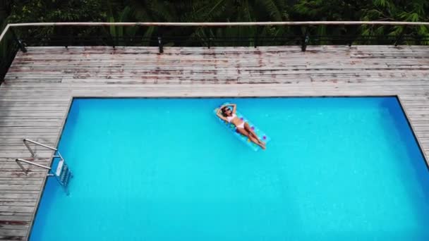 AERIAL. Vista da beleza mulheres jovens posando no colchão de ar na pesquisa de natação, villa de luxo, paraíso. Vista para a selva do drone — Vídeo de Stock