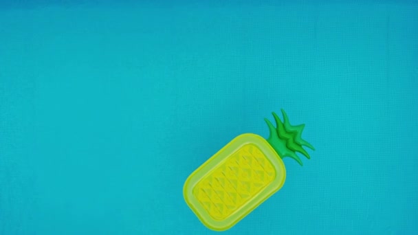 空中。漂浮的菠萝, 泳池中的沙滩床垫水晶清澈的水面, 阳光灿烂的水池循环慢运动背景 — 图库视频影像