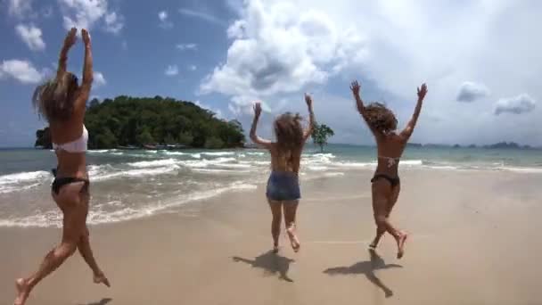Grupa czterech szczęśliwy dziewcząt uruchamia i skacze na przeciwko plaży zachód słońca nad morzem. Koncepcja tropikalny wakacje — Wideo stockowe