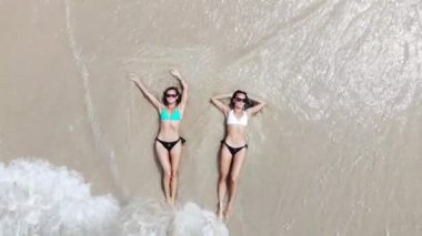 Üstten görünüm iki genç kadın yalan ve Tayland, dron havadan görünümden turkuaz deniz suyu ile beyaz kumlu sahilde rahatlatıcı bir bikini
