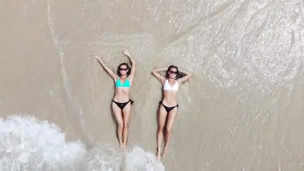トップがビキニを着て横になっているとタイ ドローンから空撮のターコイズ ブルーの海の水と白い砂浜でリラックスの つの若い女性を見る — ストック動画