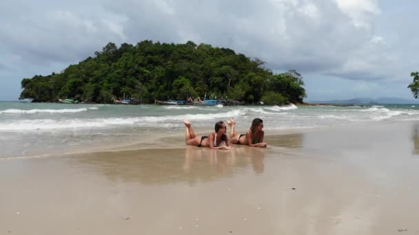 Top view two young woman in a bikini lying and relaxing on the white sandy beach with turquoise sea water of thThailand, aerial view from drone — стоковое видео