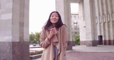 Sokak bir şehirde bir kağıt bardak kahve ile Genç Asyalı kadın. Kız kahve ile gitmek