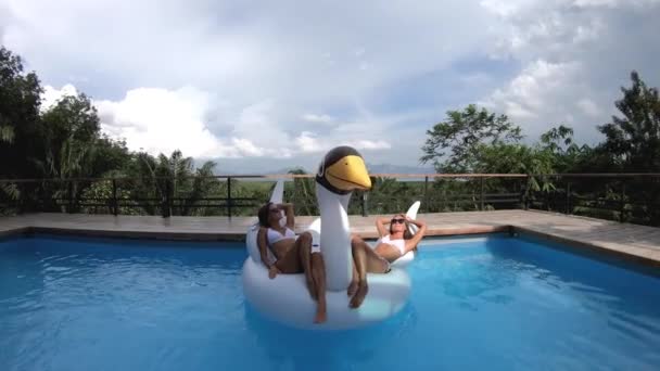 Dwie moda piękne sexy kobiety relaks na powietrzu łabędź materac w luksusowej willi przy basenie — Wideo stockowe