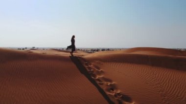Hava. Bir kadında abaya yanındaki Birleşik Arap Emirateswalking boş çeyrek çöl dunes üzerinde uçan bir uçak üzerinden görüntüleyin. Abu Dhabi, Birleşik Arap Emirlikleri.