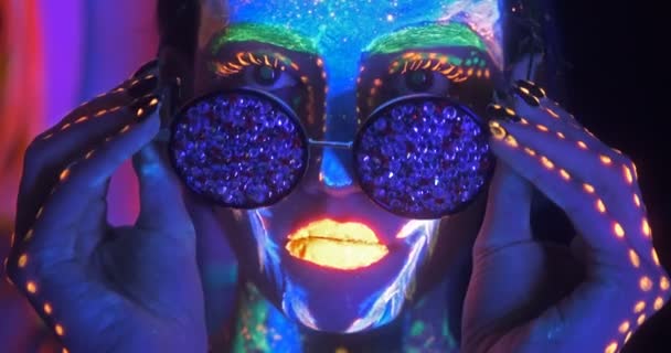Ritratto di Bella Donna di Moda in Neon UF Light togliendosi gli occhiali di moda. Modello ragazza con fluorescente creativo psichedelico MakeUp . — Video Stock