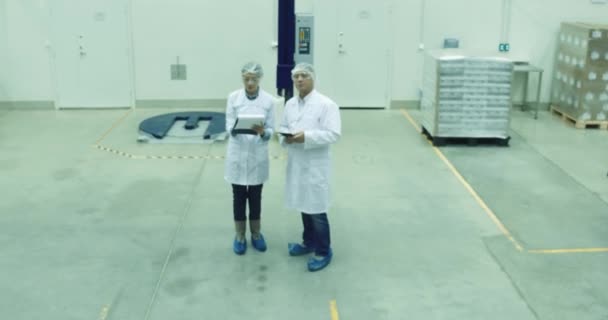 Trabajador usando tableta y hablando con colega en almacén moderno. Almacenamiento interior . — Vídeos de Stock