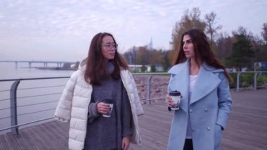 Açık havada moda portre iki neşeli kız, Asya ve Arap kahve içme. Dolgu üzerinde yürüme.