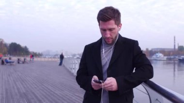 Şehir setin güzel arka plan görüntüsü üzerinde duran telefonla sohbet kulaklık ile yakışıklı adam.