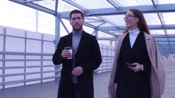 Homme d'affaires et femme d'affaires marchant le long de la rue tenant café à emporter — Video