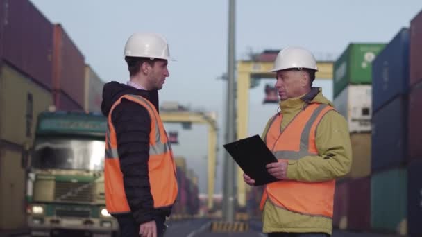 Gestore del porto e un collega tracciano l'inventario mentre sono insieme da container su una grande darsena commerciale — Video Stock