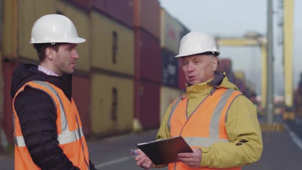 Gestore del porto e un collega tracciano l'inventario mentre sono insieme da container su una grande darsena commerciale — Video Stock