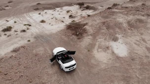 Антена. Пара всередині автомобіля білий cabrio в пустелі. — стокове відео