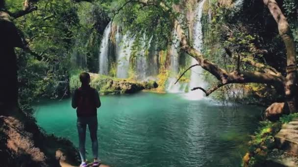 AERIAL. Женщина-путешественница смотрит на большой водопад . — стоковое видео