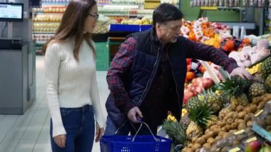 Babası süpermarkette ananas seçen Asyalı genç bir kadın.,