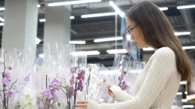 Genç Asyalı kadın süpermarkette orkide çiçeği seçiyor. Alışveriş, tüketim ve insan konsepti.