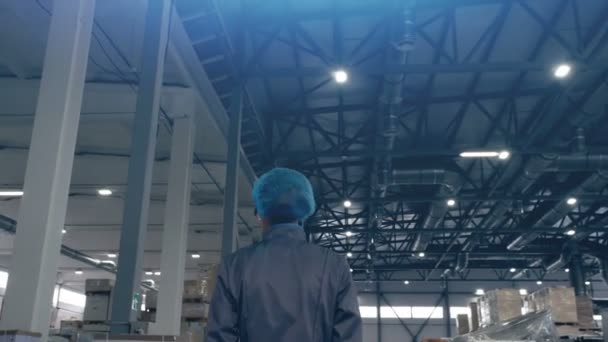 Prise de vue d'une travailleuse industrielle traversant une usine de fabrication. Clip. Vue arrière du travailleur d'entrepôt féminin portant l'uniforme . — Video