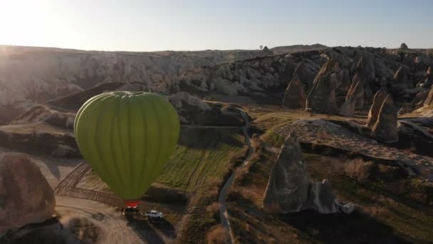 Hot air balloons flies in sunrise sky above amazing rocks with cave rooms and mountains in Cappadocia, Turkey — Stock Video