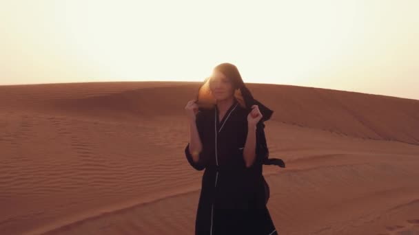 वाळवंटावर सुंदर सूर्यास्त दरम्यान पारंपारिक काळा कपडे परिधान एक तरुण अरब स्त्री पोर्ट्रेट . — स्टॉक व्हिडिओ