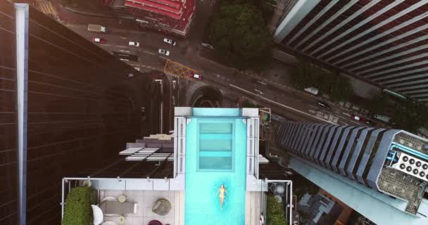 AERIAL. Top view of Hong Kong streets from the drone. And woman at the sweeming pool. — Stock Video