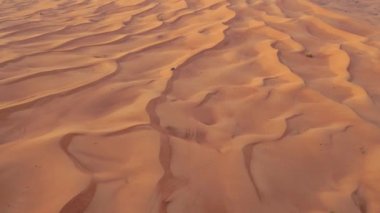 AERİAL. Arabanın üstünde yükseklik uçuşu. Çöl safarisi arabası gün batımında Dubai çölünde kum tepesi.