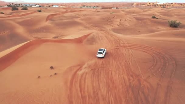 Lotnicze. Widok z góry na cztery koła jazdy samochodem na pustyni. Kamera podąża za błędem białego samochodu na pustyni — Wideo stockowe