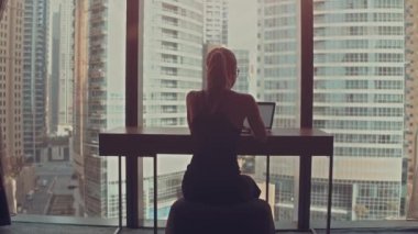 Güzel Başarılı İş Kadını Ofisinde Dizüstü bilgisayarında Şehir Manzarası Penceresi ile çalışıyor. Güçlü Independend Kadın CEO 'su İş Şirketi' ni yönetiyor. Arkasında Güneş parıldıyor.