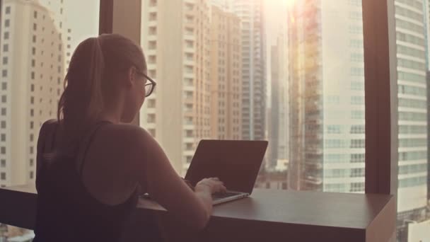 Belle femme d'affaires prospère travaillant sur un ordinateur portable dans son bureau avec fenêtre de vue paysage urbain. Strong Independend Female CEO Runs Business Company. Soleil brille derrière elle. — Video