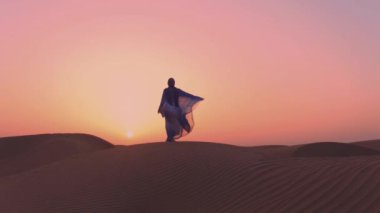 Slowmotion. Çölde ellerini kaldıran güzel mavi ve beyaz Arap kıyafetleri giyen kadınlar