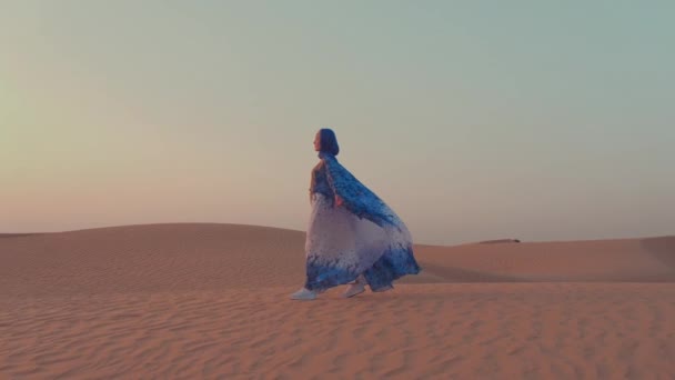 Mujeres vestidas con hermosas ropas árabes azules y blancas levantando sus manos en el desierto — Vídeos de Stock