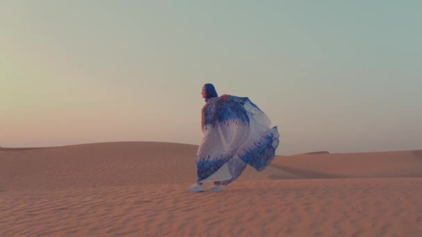 A cámara lenta. Mujeres vestidas con hermosas ropas árabes azules y blancas levantando sus manos en el desierto — Vídeos de Stock