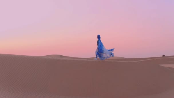 Femmes portant de beaux vêtements arabes bleus et blancs levant les mains dans le désert 