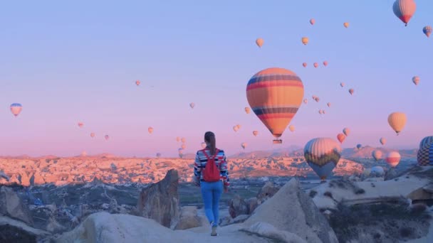 Žena cestovatel s batohem s výhledem na vzduchové baloony. sportovní holka a spousta horkovzdušných balónků. Pocit naprosté svobody, úspěchu, úspěchu, štěstí — Stock video