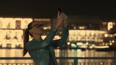 Rahat giyim güzel genç kız bir akıllı telefon kullanarak fotoğraf yapar