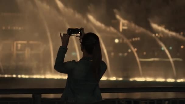 Vue arrière d'une jeune touriste mince enchantée prend des photos de fontaines festives — Video